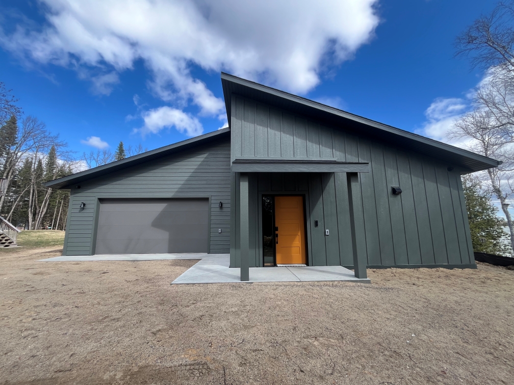 modern exterior black siding and orange door